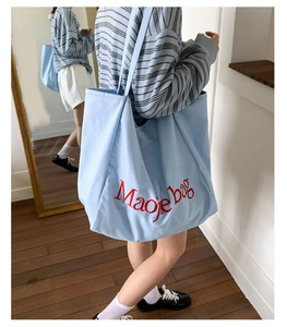 Grand sac cabas en toile bleu clair avec broderie Maoje rouge utilisé par un mannequin