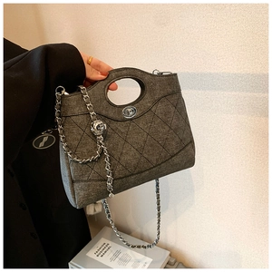 Détail du sac à main en denim matelassé gris avec chaîne argentée et fermoir pivotant