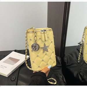 Close-up of quilted yellow phone bag with star charm and metal chain strap details