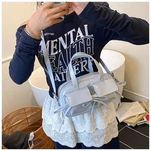 Détail du sac bowling bleu clair métallisé avec nœuds et poches frontales