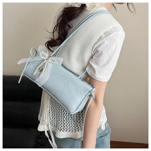 Détail du sac à bandoulière bleu clair avec fleurs en relief, nœud dentelle et perles