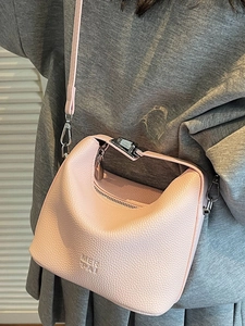 Pink lychee grain leather handbag with crossbody strap shown in a stylish fashion lifestyle