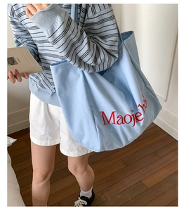 Détail du sac cabas en toile bleu clair avec broderie de lettres rouges de qualité