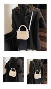 Détail du sac en cuir crème montrant la poignée ronde et le rabat sur fond de bois sombre