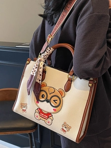 Large cream leather tote bag with cartoon bear print and stylish scarf on the handle