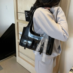 Borsa tote nera lucida Y2K con tasche e decorazione in pizzo sulla spalla della modella