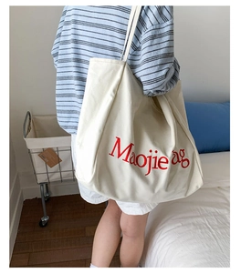 Détail d'un sac cabas en toile avec broderie de lettres rouges en décor quotidien