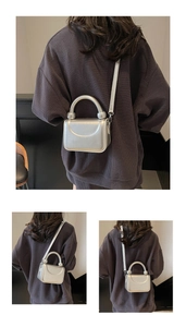 Détail d'un mini sac carré argenté avec poignée sphérique et bandoulière élégante