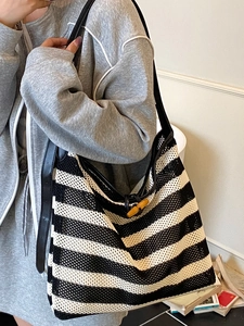 Women's minimalist black and white striped woven tote bag with leather straps on model