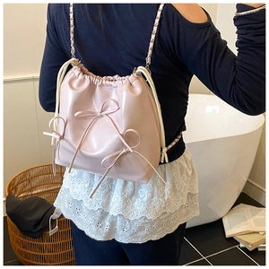 Detail of pink glossy drawstring bucket backpack with ribbon bows and chain straps