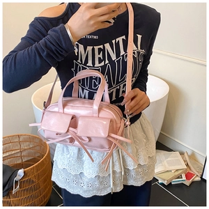 Sac bowling rose en similicuir avec poches décoratives et lanières porté par un mannequin