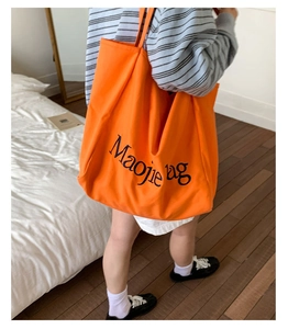 Détail du grand sac cabas en toile orange vif avec des lettres artistiques noires dessus