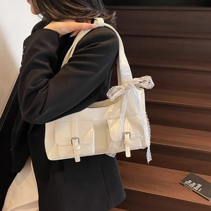 Borsa tote crema con dettaglio fiocco e fibbie argentate su sfondo di legno