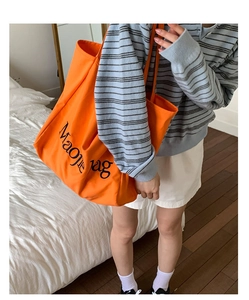 Détail d'un grand sac cabas en toile orange avec inscription noire Maojie Bag