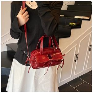 Gros plan d'un sac baguette en cuir verni rouge avec nœuds et deux poches frontales