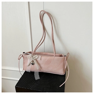 Détail du sac sous le bras rose gaufré avec nœud en dentelle, perles et breloque cœur