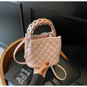 Detail of pink quilted bucket bag with rhinestones and woven chain handle held by hand