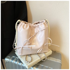 Detail of a chic bucket bag featuring three large bows and silver-tone chain straps