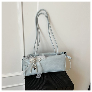Détail du sac sous le bras bleu clair avec nœud en dentelle et motifs floraux