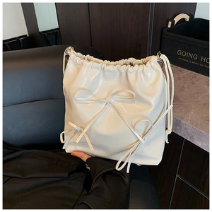 Close-up of cream bow drawstring backpack with glossy synthetic leather texture