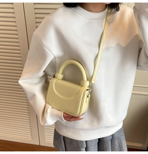 Gros plan du mini sac à main en cuir verni jaune clair avec poignée et fine bandoulière