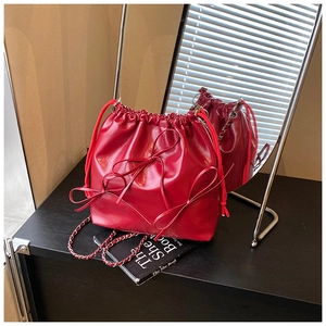 Detail of red drawstring bucket bag with bow decoration and leather chain strap