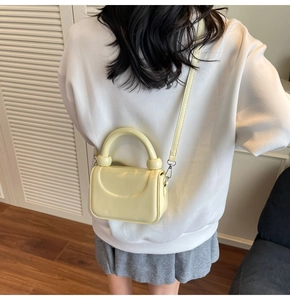 Détail montrant la vue arrière du mini sac jaune crème brillant avec bandoulière