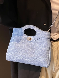 Sac seau en denim matelassé bleu clair avec bandoulière chaîne argentée porté par un mannequin