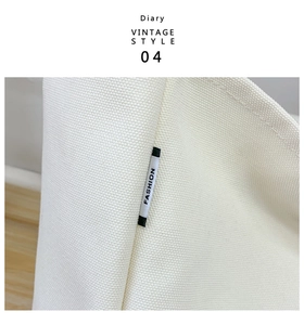 Primer plano del bolso de lona crema mostrando las costuras y etiqueta de moda