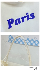 Detalle de cerca del bolso tote de lona blanca con estampado de letras Paris en azul