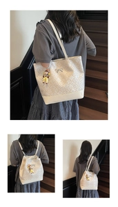 Detail view of cream tote bag with geometric print, silver bow, and cute doll pendant
