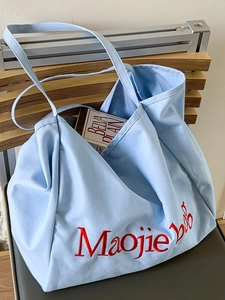 Grand sac fourre-tout en toile bleu clair avec broderie rouge sur une chaise