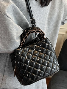 Chic black quilted bucket bag with rhinestones and woven handle on model shoulder