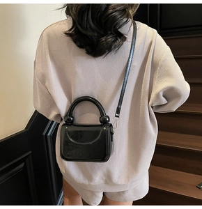 Sac à main chic en cuir verni noir avec poignée ronde sur un sac à bandoulière