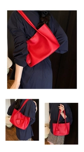 Detail of red pebbled leather tote bag with round leather charm and long shoulder strap