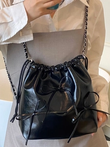 Fashionable black drawstring bucket bag with bow accents and silver chain strap