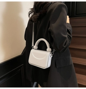 Petit sac à main chic gris clair avec poignée anneau argentée porté à l'épaule, style moderne