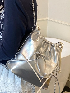 Silver metallic bucket backpack with chain strap and bow details for trendy summer travel