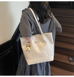 Detail of cream white tote bag with geometric jacquard pattern and silver bow charm