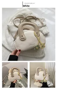 Détail du sac à main en cuir beige avec breloques fleurs et poignée supérieure arrondie