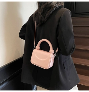 Vue détaillée du mini sac à main structuré rose avec poignée ronde sur blazer noir
