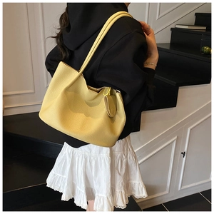 Close-up of a large yellow tote bag with litchi texture on a model at a staircase