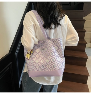 Rear view of a model carrying the purple floral tote bag with a cute bear charm accessory