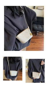 Détail d'un mini sac seau blanc crème avec texture crocodile et breloque dorée en cacahuète