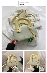 Détail du mini sac vert en cuir grainé avec poignée jaune et breloques de fleurs
