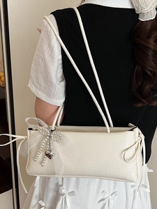 Sac sous le bras blanc crème avec nœud en dentelle et perles porté par le mannequin