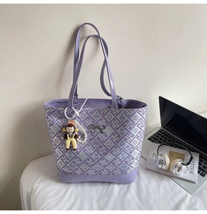 Detail of purple tote bag with geometric weave, silver bow, and pearl chain accessory