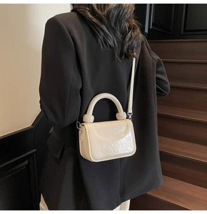 Détail du petit sac bandoulière crème en cuir grainé avec crochets métalliques
