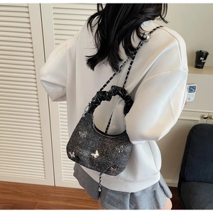 Detail of grey shimmer fabric bag with silver butterfly charms and chain strap