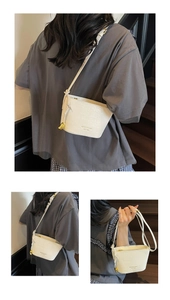 Détail du sac seau blanc à motif crocodile avec ornements dorés et bandoulière